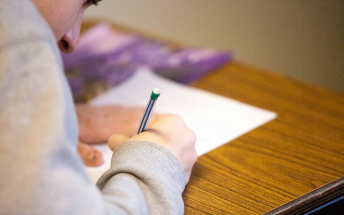 Person writing an exam with a pencil